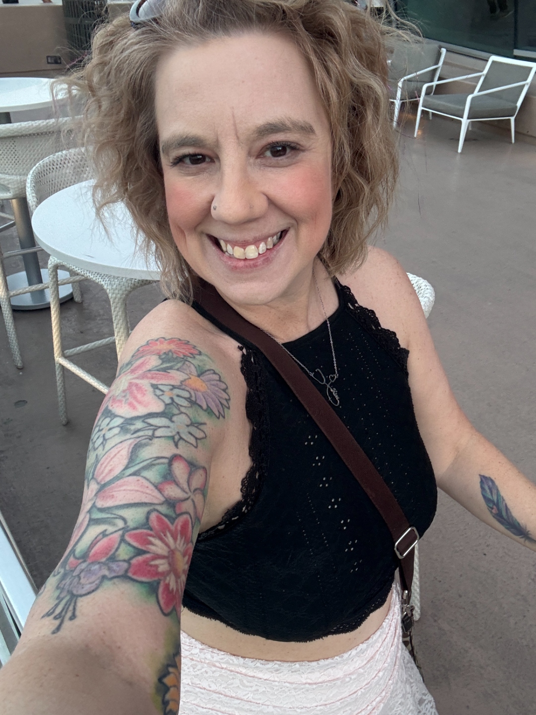 Kim — the real face behind PinkTco. Curly hair, flower tattoo sleeve, big smile.